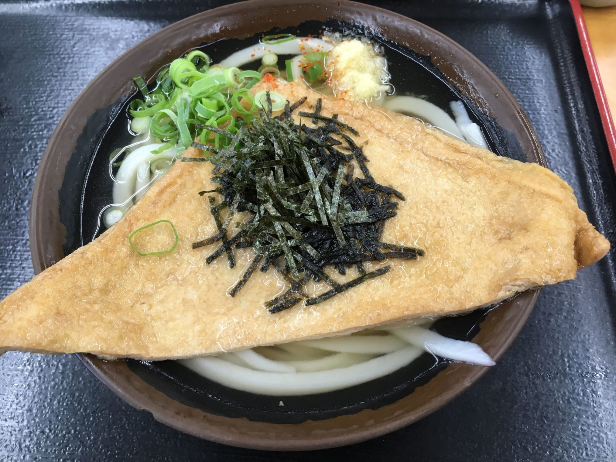 「さぬき麺輝屋 土器店」の、どんぶりの端からはみ出す『かけうどん+お揚げ』